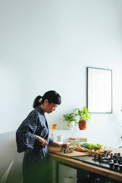 istock Happy Woman Cutting Sushi Rolls In The Kitchen 1475127131