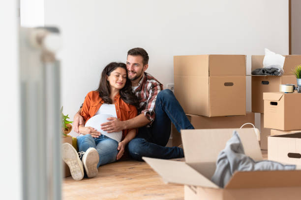 istock Young happy couple moved into an empty apartment sitting among cardboard boxes 1475129998