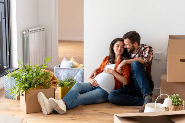 istock Young happy couple moved into an empty apartment sitting among cardboard boxes 1475130690