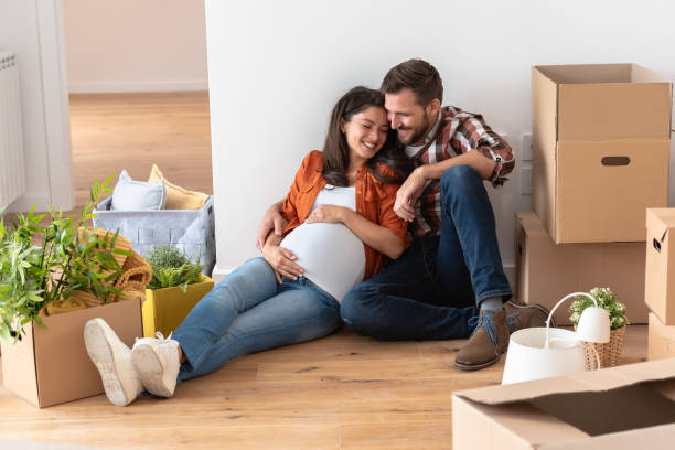 istock Young happy couple moved into an empty apartment sitting among cardboard boxes 1475130993