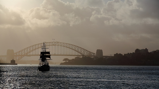 Silhouetted schooner barque tall ship sailing towards Harbour Bridge in a hazy afternoon. Sydney-Australia-561