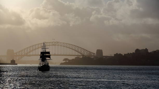 silhuetado escuna barca navio alto navegando em direção a harbour bridge em uma tarde nebulosa. sydney-austrália-561 - mizzen - fotografias e filmes do acervo