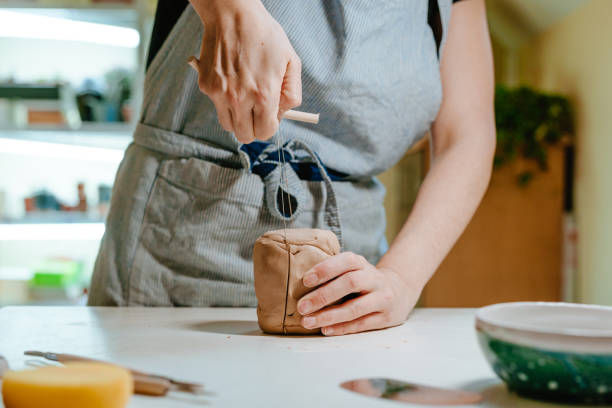 istock Young woman potter cutting clay with a special tool 1475131979