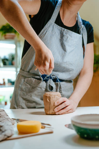 istock Young woman potter cutting clay with a special tool 1475131984