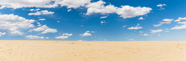 Sand dunes and blue sky with white clouds, natural background.