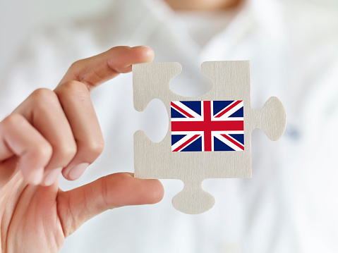 Businesswoman holding jigsaw puzzle pieces with British flag