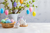 Easter composition with crafted Easter bunny, colorful eggs and flowering willow decorated with Easter eggs.