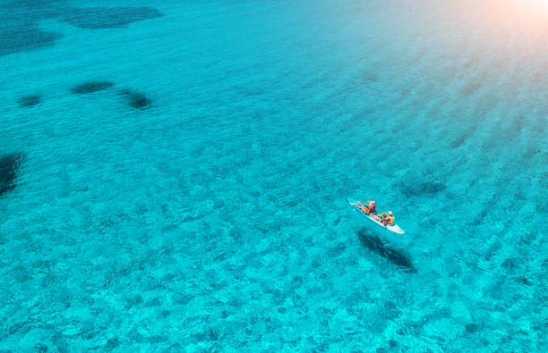 Aerial view of kayak with people in blue sea at sunset in summer stock photo