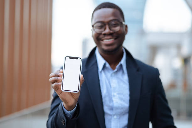 istock Young African American man showing smart phone with a blank screen 1475139893