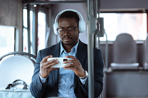 African-American man in the public bus holding a mobile phone and watching online content