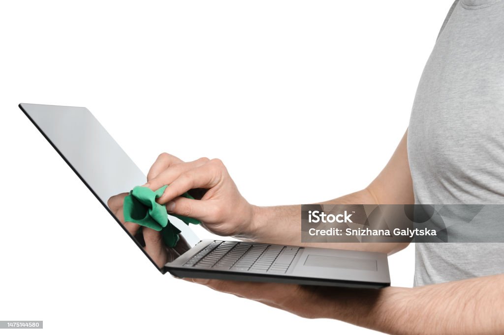 A man in a gray T-shirt wipes the screen of an ultrabook, laptop with a green rag Adult Stock Photo