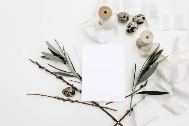 istock Easter, spring still life. Blank greeting card, invitation mockup isolated on white table background. Quail eggs, silk ribbons, green olive tree branches and catkins.Feminine styled photo, flat lay, top view. 1475145980
