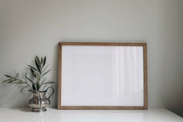 istock Empty horizontal wooden picture frame mockup. Olive tree branches in silver jug vase. Mint green wall background. Working space, home office. Art, poster display. Retro summer interior still life. 1475146082