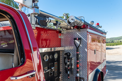 Close up view of rear fire truck has water control panel on side along with breaching tools to handle any type of rescue.