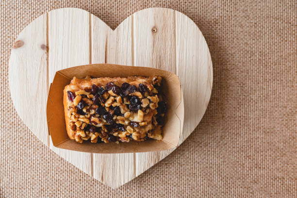 Raisin Walnut cinnamon roll close up on a wooden heart-shaped board, flat lay with copy space