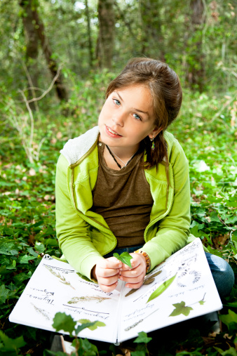 Young girl with herbarium in the woods.
