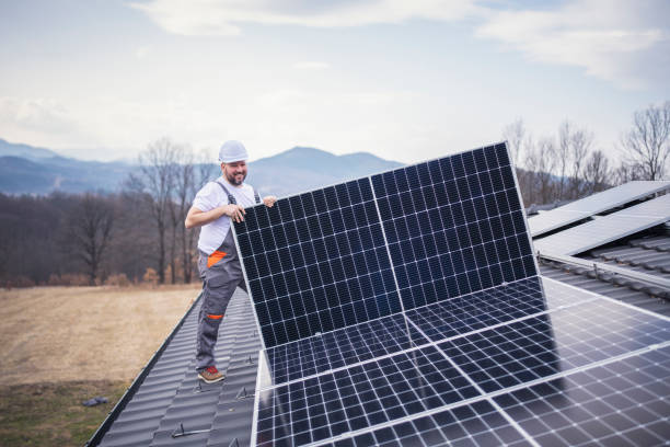istock Solar panel installer installing solar panels on roof of modern house. 1475150452