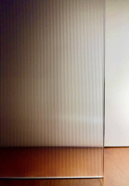 Direct view of vertical stripe reeded glass with backlighting. Direct view through vertical stripes of corrugated glass. Clear fluted glass with back light against white paper background. frosted glass door office stock pictures, royalty-free photos & images