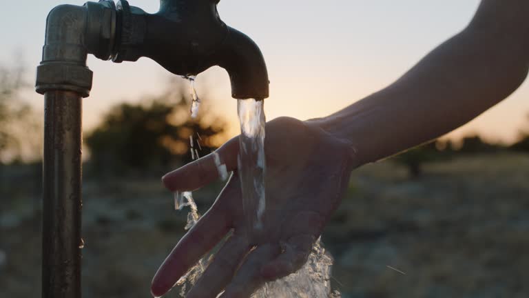 woman washing hand under tap on rural farm at sunset freshwater flowing from faucet