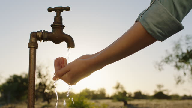woman hands catching water under tap thirsty farmer drinking freshwater flowing from faucet at sunset save water concept