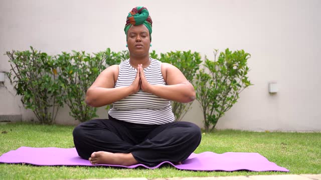Black mature woman meditating in backyard
