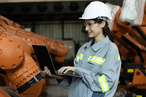 Female Engineer Wearing Hard Hat, Standing, Using Laptop. Monitoring, Control, Equipment Production