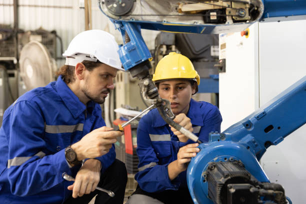 istock Two men and female engineer using tools adjusting robotic arm in factory 1475163322