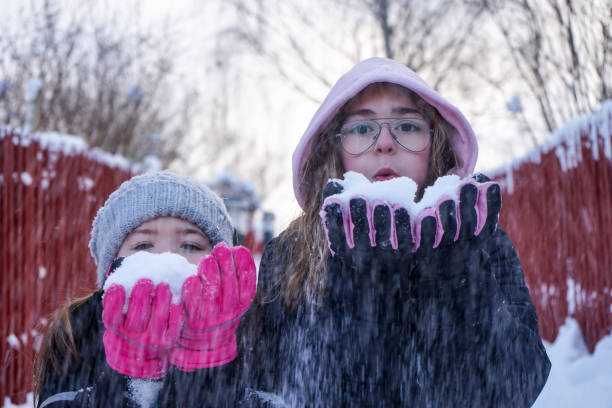 портрет друзей, держащих снег во время игры на открытом воздухе зимой - sibling sweden family smiling стоковые фото и изображения