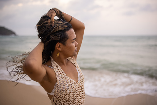 Transgender Asian woman woman standing on the beach by the sea.