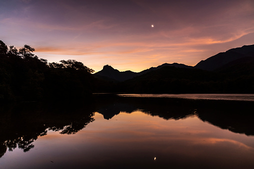 Beautiful sunset with orange clouds over rainforest lake in Guapiaçu, Rio de Janeiro, Brazil