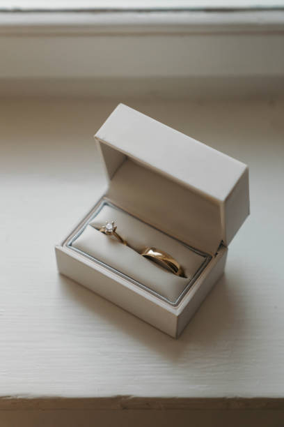 istock Golden wedding rings in white ring box, on white wooden surface 1475169616