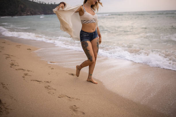 One woman, beautiful woman having walking on the beach by the sea alone.