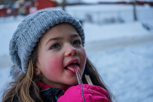 Close up of cute girl licking ice cube during winter