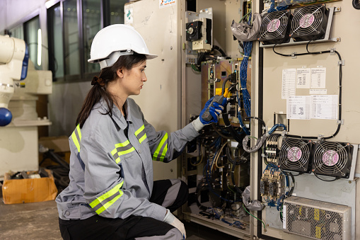 Female engineer using multimeter measurement control box in factory