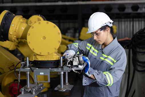 Female engineer using tools adjust machine in factory