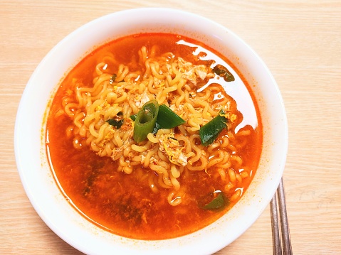 Korean spicy instant noodles in a bowl on wooden table background