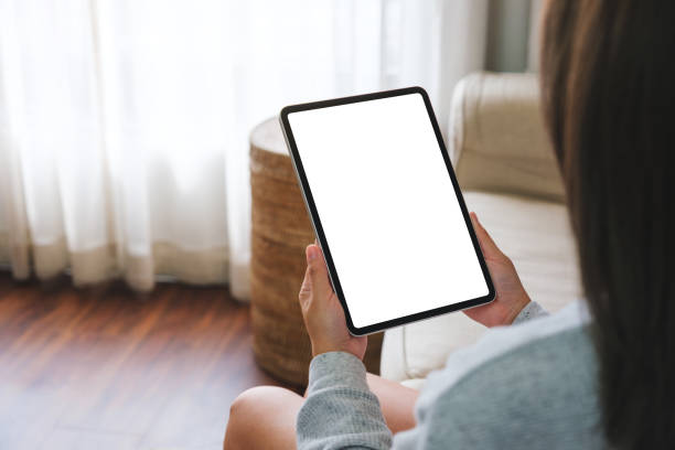 istock Mockup image of a woman holding digital tablet with blank desktop screen while lying on a sofa at home 1475180620