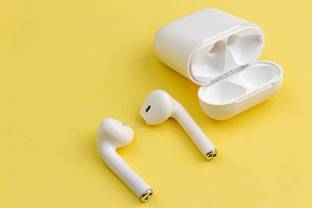 istock Modern white wireless bluetooth earphones with charging case isolated on yellow background. 1475182375