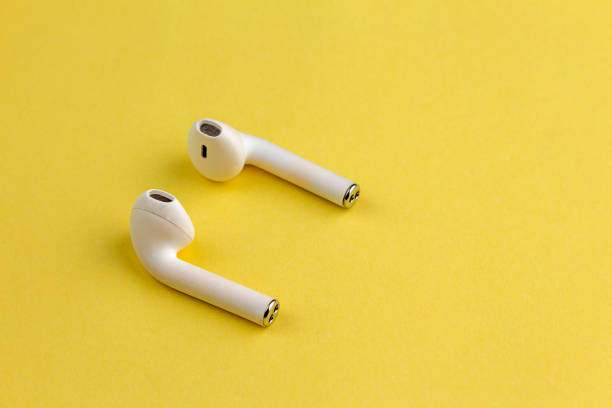istock Modern white wireless bluetooth earphones with charging case isolated on yellow background. 1475182377