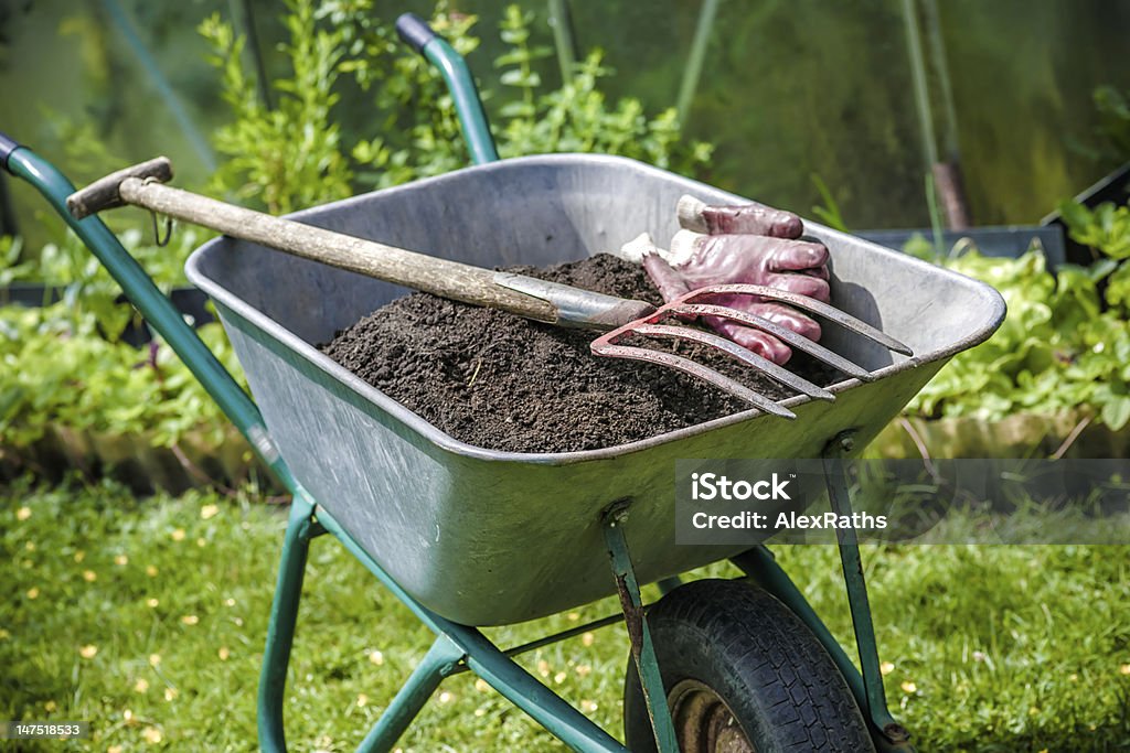 Gardening gardener with a wheelbarrow full of humus in the garden Yard - Grounds Stock Photo