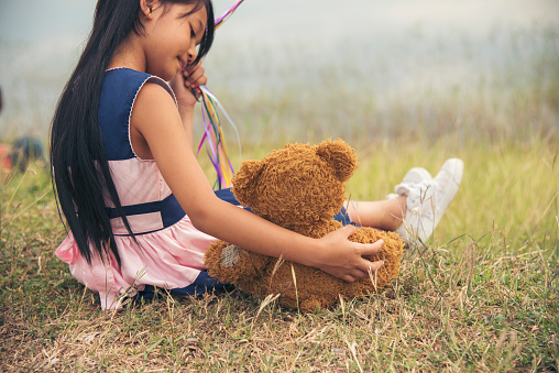 Happy Child hug teddy bear in green park playground. Teddy bear best friend for little kids cute girl. Autism happy funny playing together on playground in happiness family feel love and warm hugs