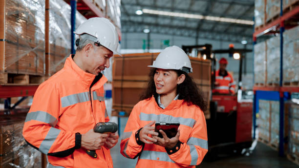 un employé d’entrepôt asiatique plus âgé expliquant le processus de travail au nouvel employé. - digital tablet warehouse commercial dock manual worker photos et images de collection