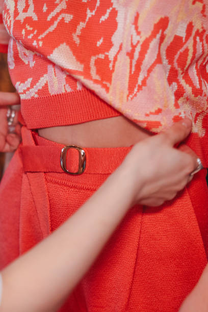 mãos femininas ajustando suéter laranja brilhante em um modelo de moda nos bastidores - hot couture - fotografias e filmes do acervo