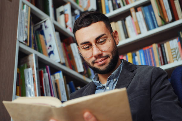 istock Man in eyeglasses reading book in book shop 1475198342