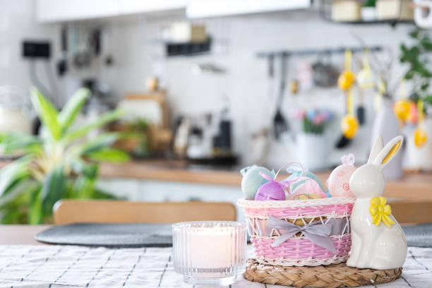 istock Easter decoration of colorful eggs in a basket and a rabbit on the kitchen table in a rustic style. Festive interior of a country house 1475198635