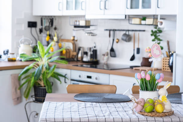 istock Easter decoration of colorful eggs in a basket and a rabbit on the kitchen table in a rustic style. Festive interior of a country house 1475198656