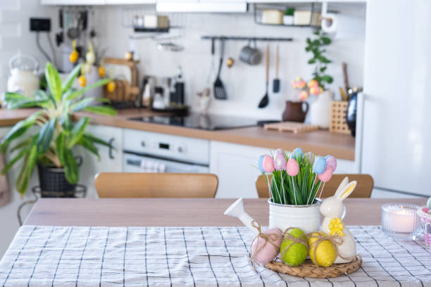 istock Easter decoration of colorful eggs in a basket and a rabbit on the kitchen table in a rustic style. Festive interior of a country house 1475198658