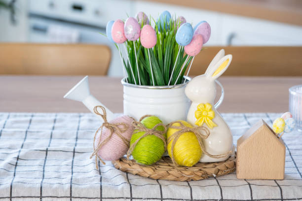 istock Easter decoration of colorful eggs in a basket and a rabbit on the kitchen table in a rustic style. Festive interior of a country house 1475198659