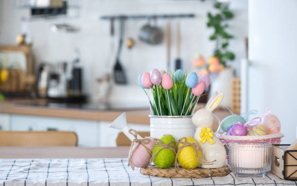 istock Easter decoration of colorful eggs in a basket and a rabbit on the kitchen table in a rustic style. Festive interior of a country house 1475198668