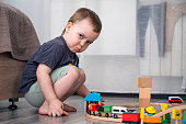 Cute displeased kid playing railroad on the floor